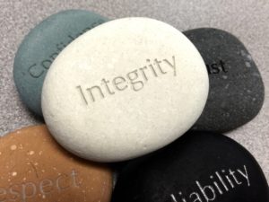 Pile of stones with words etched in them with a white one that says "Integrity" on top