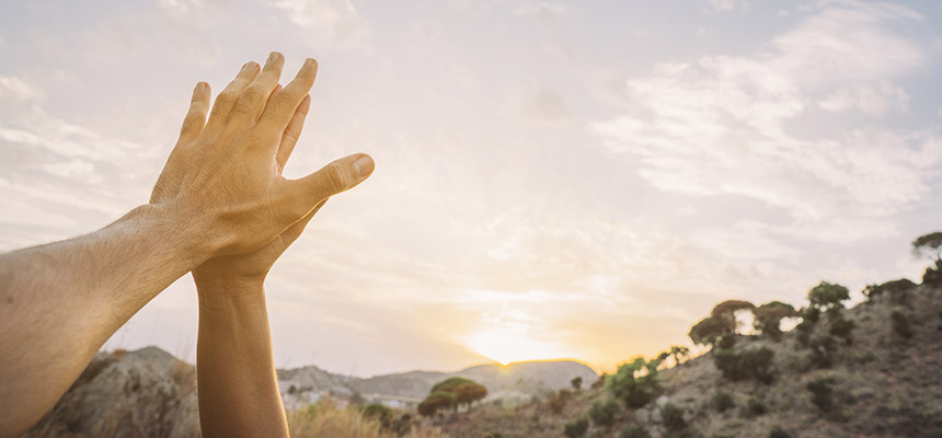 hands high fiving in front of a sunset