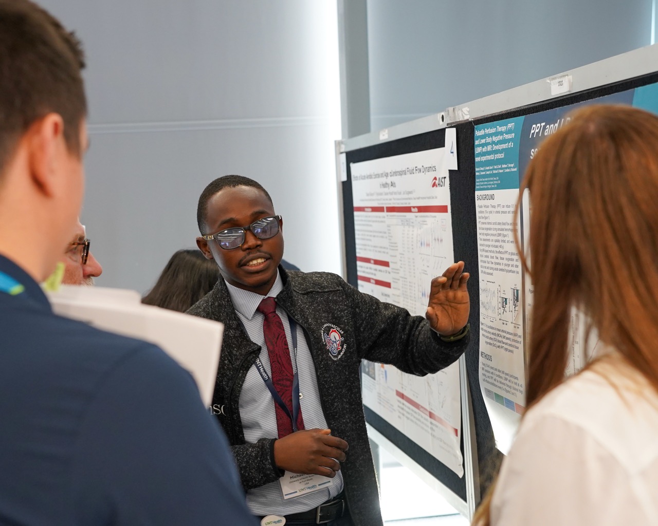 Person presenting information, standing in front of a scientific poster