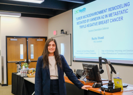 Rucha Trivedi stands in front of a presentation screen