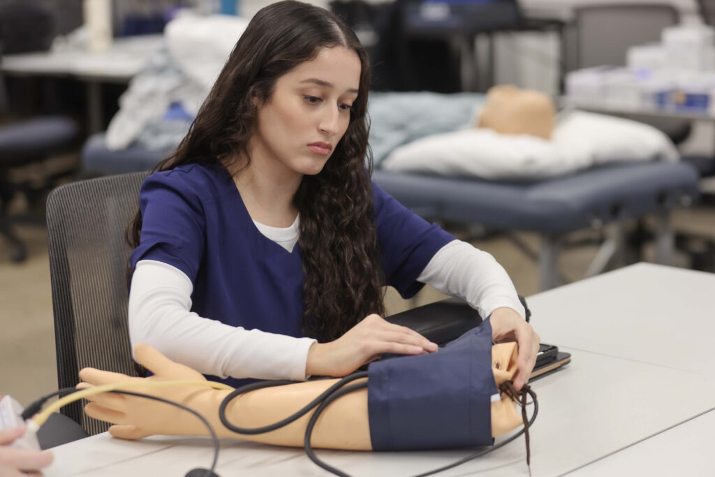 A nursing student practices using a blood pressure cuff.