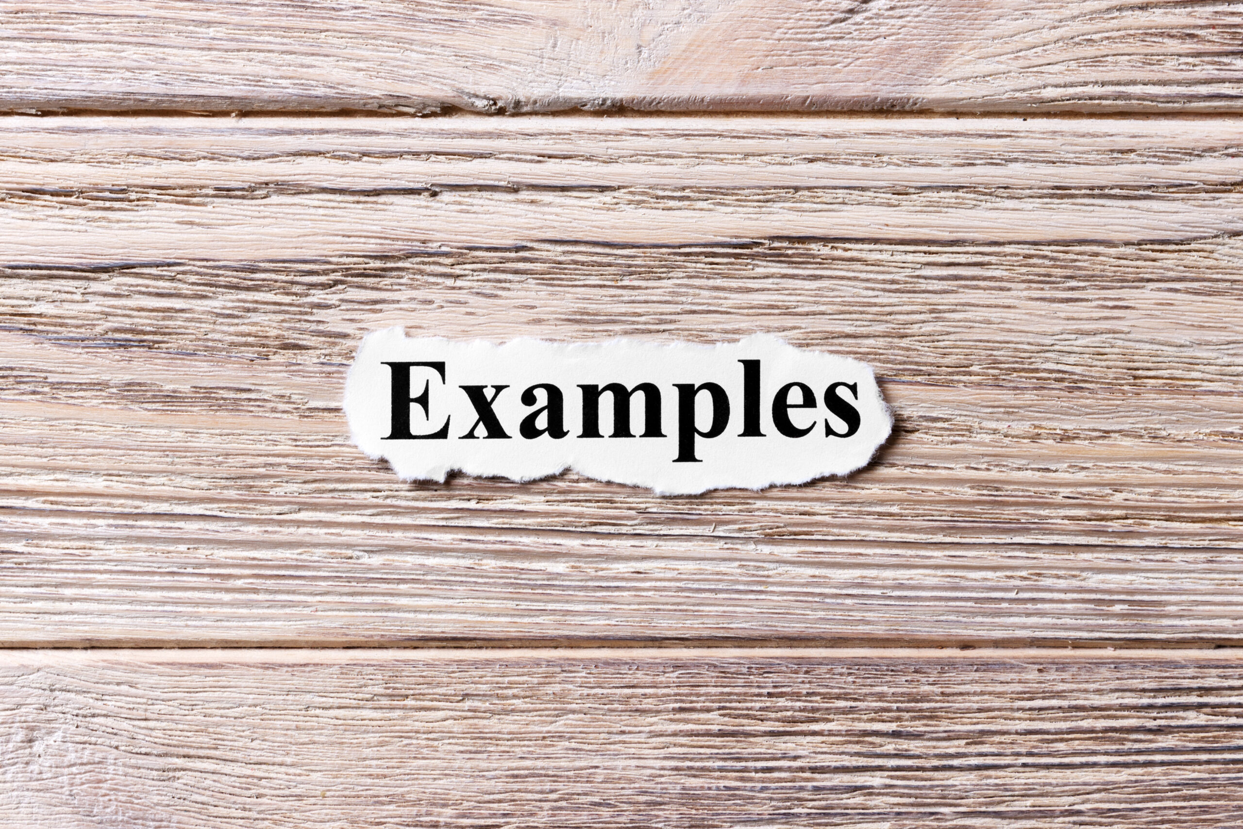 Paper with the word "Examples" on a wood background