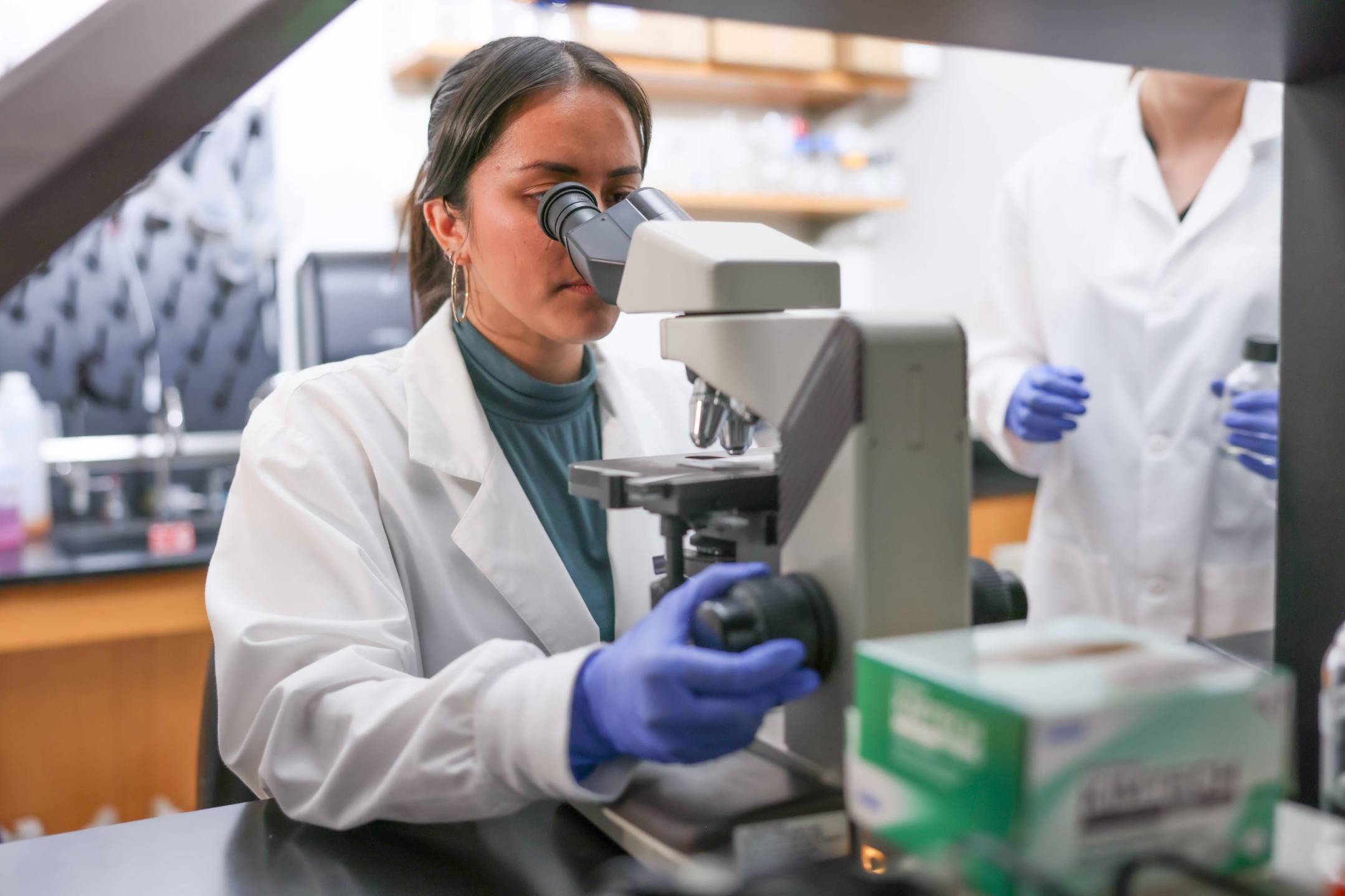 female researcher looking through a microscope