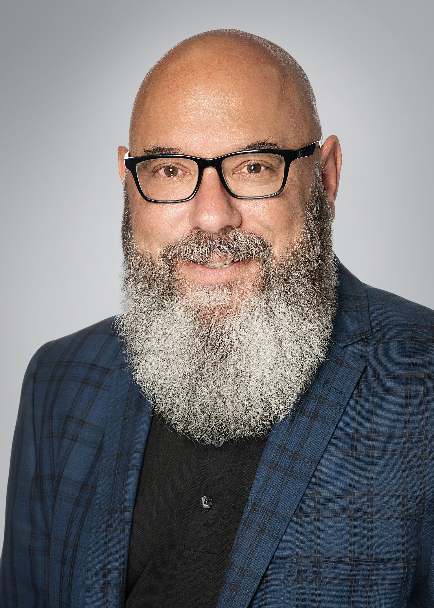 Dr. Filipetto headshot, glasses, black shirt, blue and black plaid coat