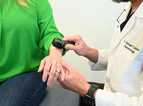 Dr. Michael Carletti examining a patient's skin