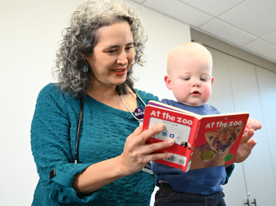 Dr. Pamela Barrera reading a book with a pediatrics patient
