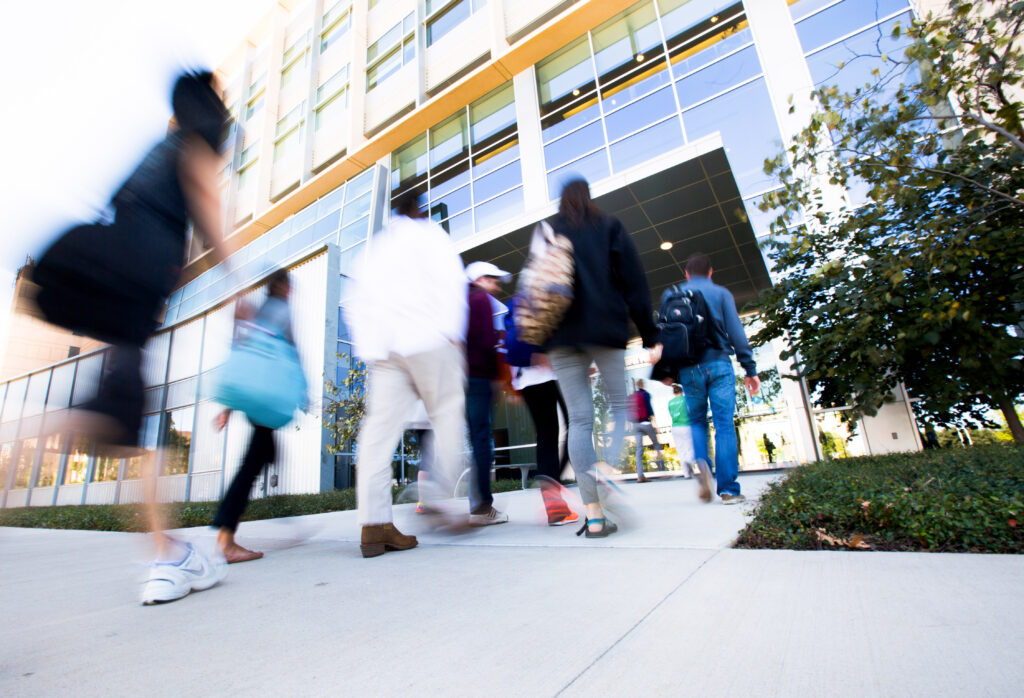 Photograph of students walking into a campus building from outdoors.