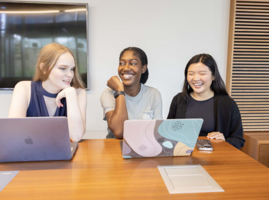 3 female students sitting together with their laptops open