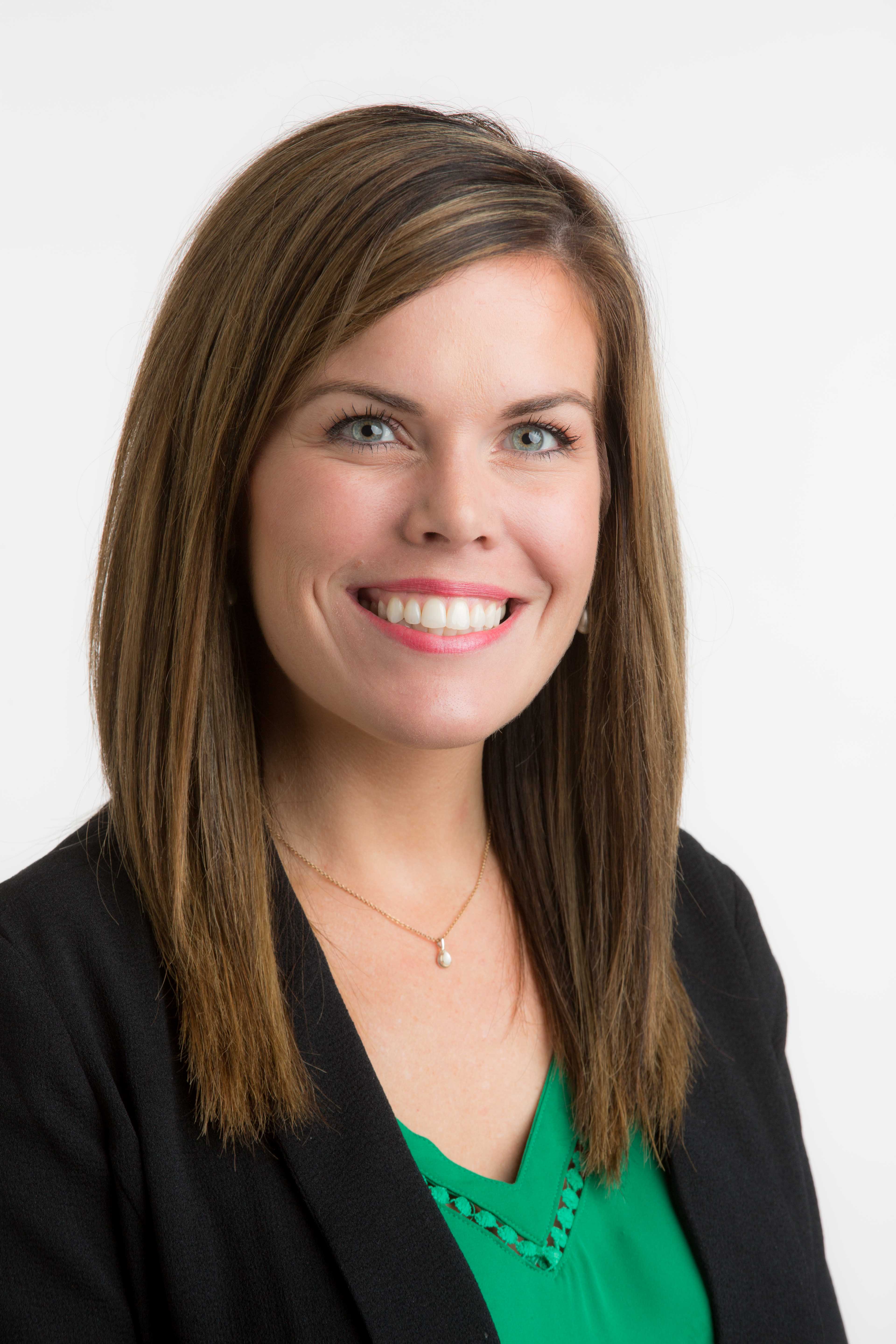 Tamara Willmoth headshot wearing a blazer and green shirt with a white background
