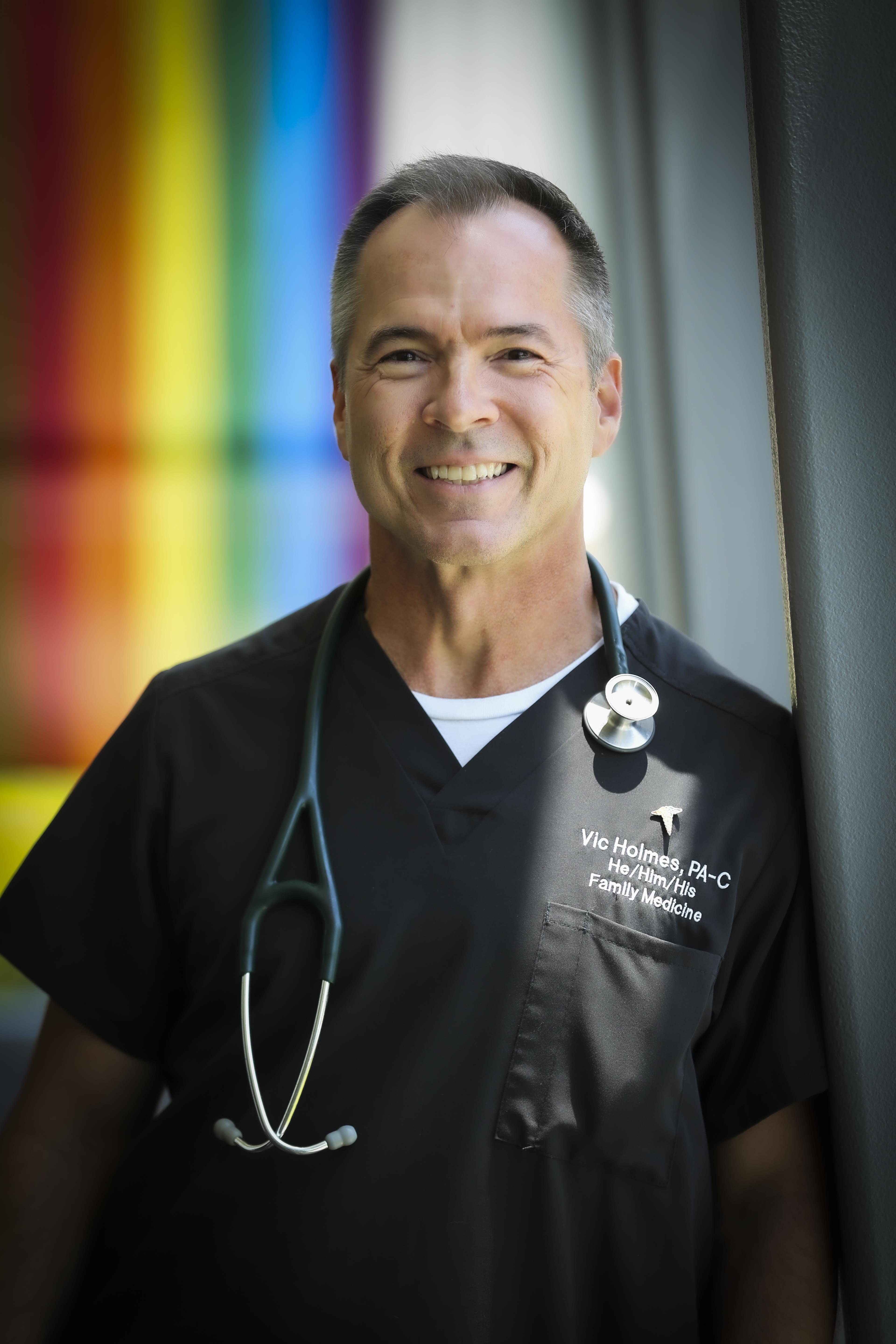 Victor Holmes headshot wearing black scrubs
